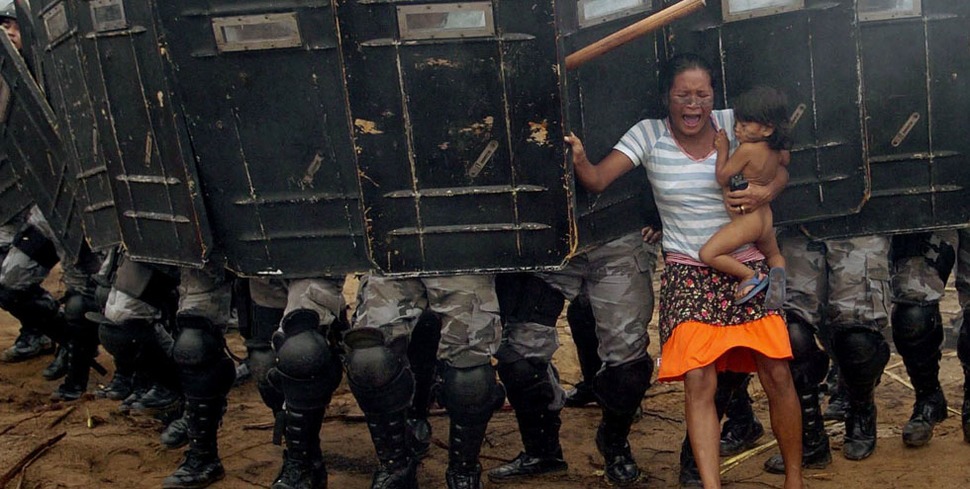 Kobieta trzymająca dziecko próbuje oprzeć się brazylijskiemu oddziałowi policji, powołanemu aby wyeksmitować mieszkańców Manaus. (2008)