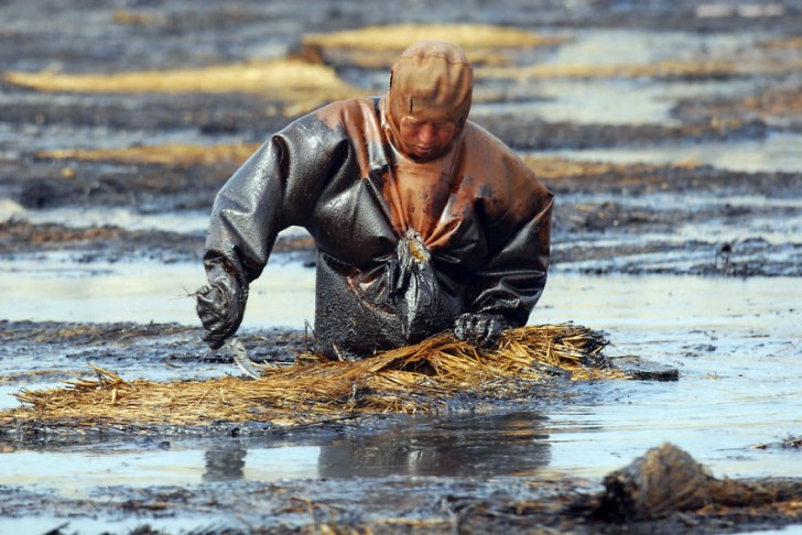 Robotnik próbuje oczyścić wodę z ropy. Dalian, Liaoning.