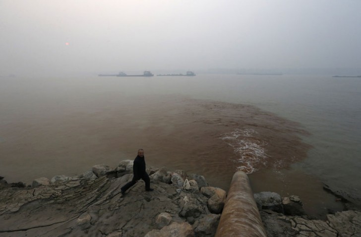 Mężczyzna spacerujący obok rury wylewającej zanieczyszczenia do rzeki Jangcy.