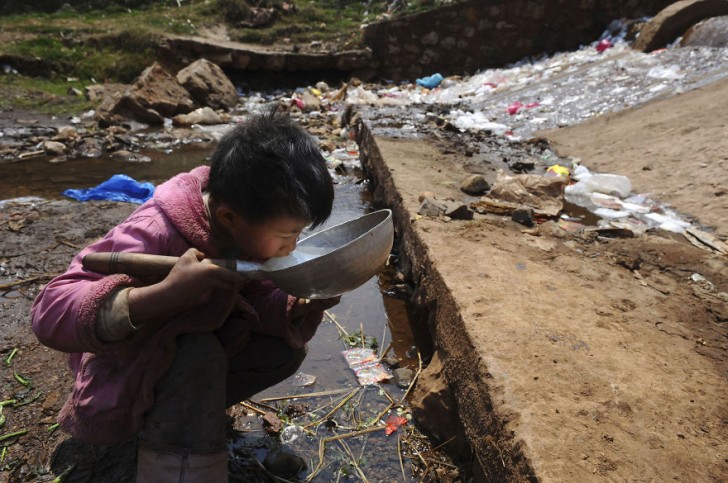 Dziecko pijące wodę ze strumienia. Fuyuan, prowincja Yunnan.