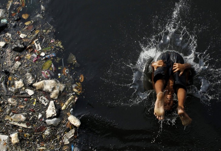 as-our-world-grows-its-becoming-disturbingly-polluted-this-boy-cannonballs-into-a-polluted-river-in-jakarta-indonesia-while-piles-of-garbage-drift-by-next-to-him