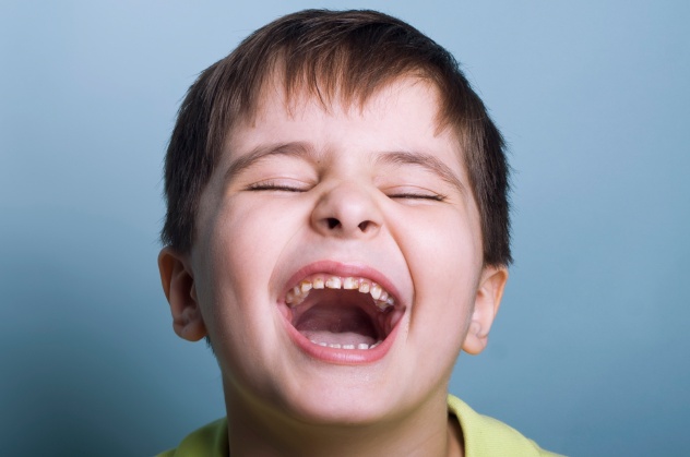 Ultimately emotional portrait of a boy crying or laughing with mouth open and marks of chocolate oh his teeth. Studio horizontal shot