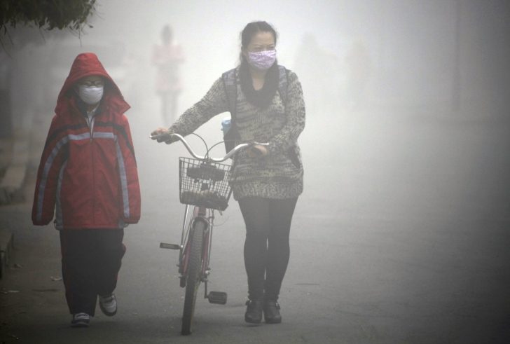 Zdjęcie przedstawia Chińczyków poruszających się w gęstym smogu.