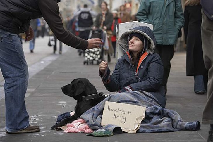 Person giving cup to homeless woman