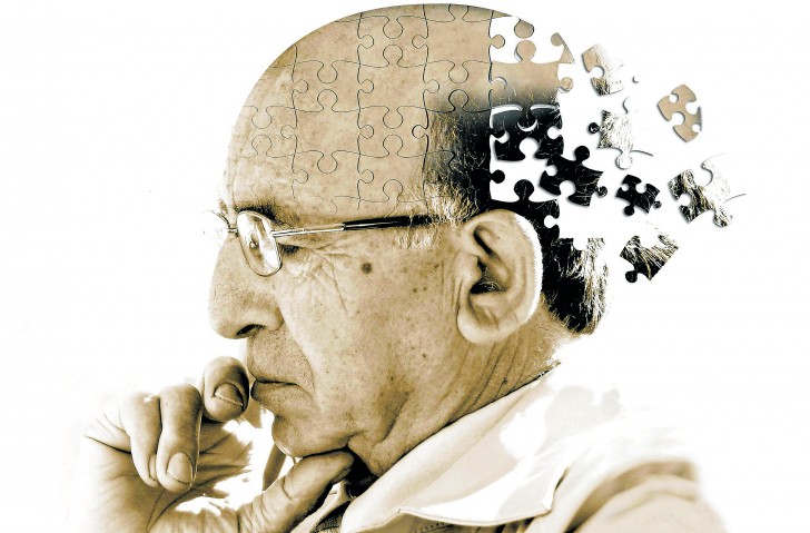 Artystyczna wizja przedstawiająca chorobę Alzheimera. Obrazek przedstawia mężczyznę w podeszłym wieku w zamyślonej pozie. Tylna część jego głowy odlatuje w formie pojedynczych puzzli poza krawędź obrazka. Przedstawia to spadek sprawności umysłowej oraz zanik pamięci.