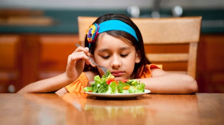 Na zdjęciu dziewczynka niechętnie spożywająca swój posiłek.