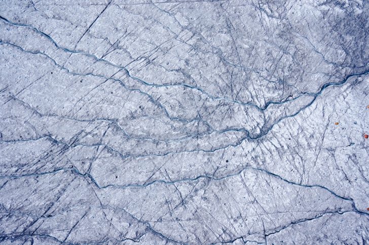 Zdjęcie przedstawia widok z lotu ptaka na teren badań. Całość obszaru pokryta jest lodem. W prawej części zdjęcia widoczne są pomarańczowe punkty (prawdopodobnie namioty badaczy).